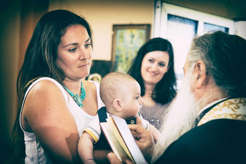 Infant's feet ascending from baptismal font water during baptising in Greece photographer