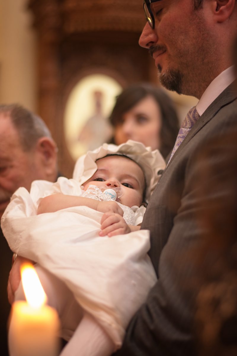 Infant's feet ascending from baptismal font water during baptising in Greece photographer