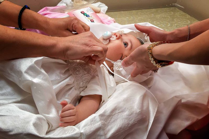 Infant's feet ascending from baptismal font water during baptising in Greece photographer