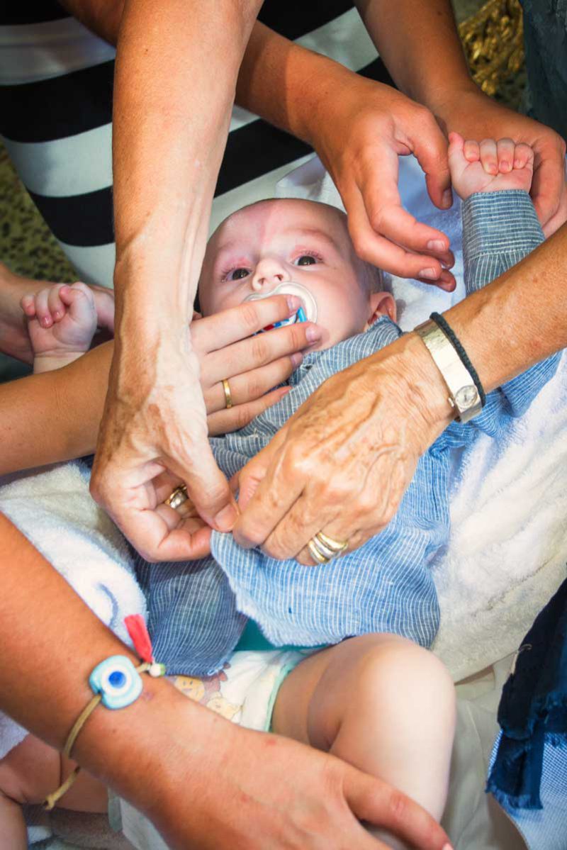 Infant's feet ascending from baptismal font water during baptising in Greece photographer