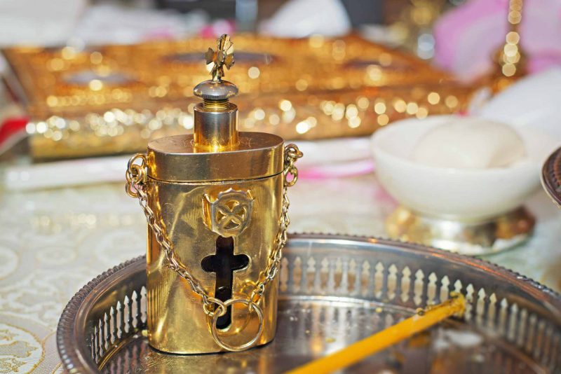 Infant's feet ascending from baptismal font water during baptising in Greece photographer