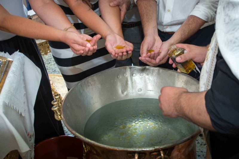 Infant's feet ascending from baptismal font water during baptising in Greece photographer