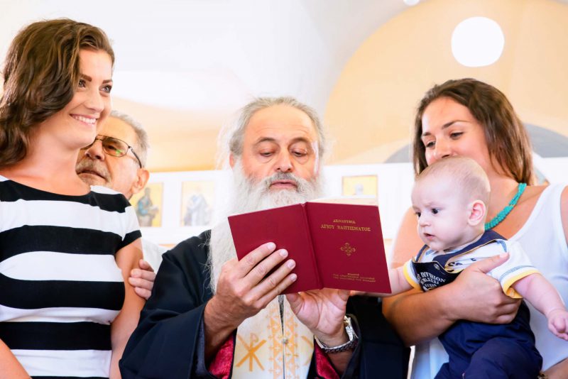 Infant's feet ascending from baptismal font water during baptising in Greece photographer